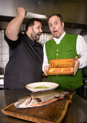 Keine Angst, Fischlieferant Werner Mühle passiert nichts, an den Kragen will Küchenchef Christoph Schmid lediglich dessen köstlichen Lachsforellen, die er als Zirbenfisch serviert. (Foto: Harald Steiner Fotografie)